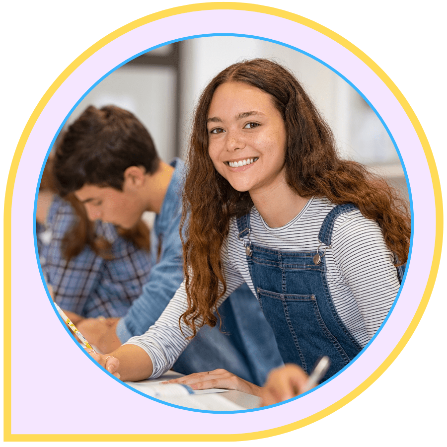A bright, smiling student working at a school desk